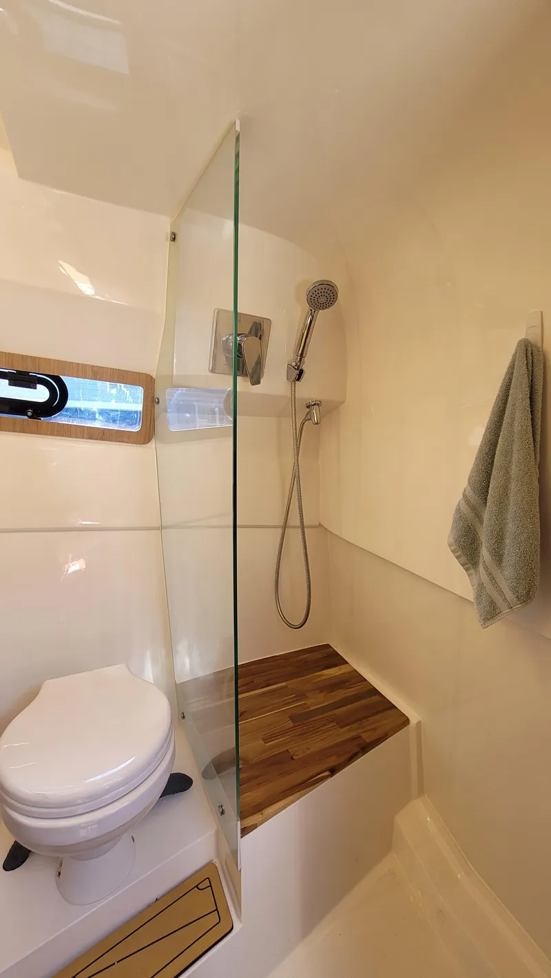 Slide: The Image of 2023 NX Boats NX340 bathroom with shower, toilet, and wooden accents. - 25