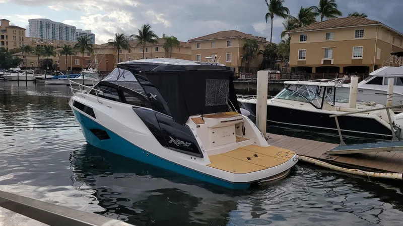Slide: The Image of 2023 NX Boats NX340 docked in a marina with palm trees and buildings. - 6