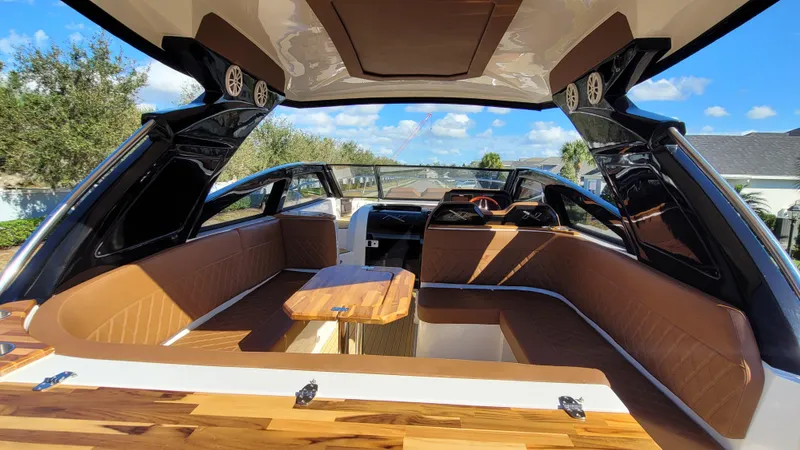 Slide: The Image of 2023 NX Boats NX340 interior with luxurious seating and wooden table under a sunny sky. - 7