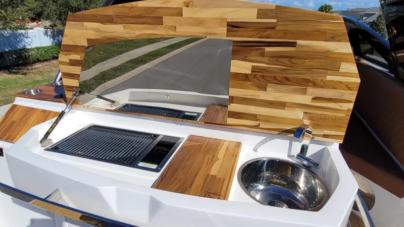 Slide: The Image of 2023 NX Boats NX340 outdoor kitchen with wooden accents and stainless steel sink. - 8
