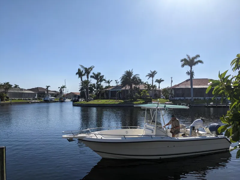 Slide: The Image of 2003 Pursuit 2470 Center Console boat on a sunny canal with palm trees. - 1