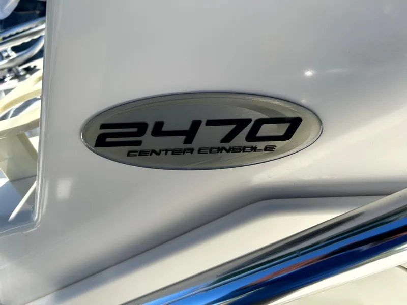 Slide: The Image of 2003 Pursuit 2470 Center Console boat emblem on white surface. - 12