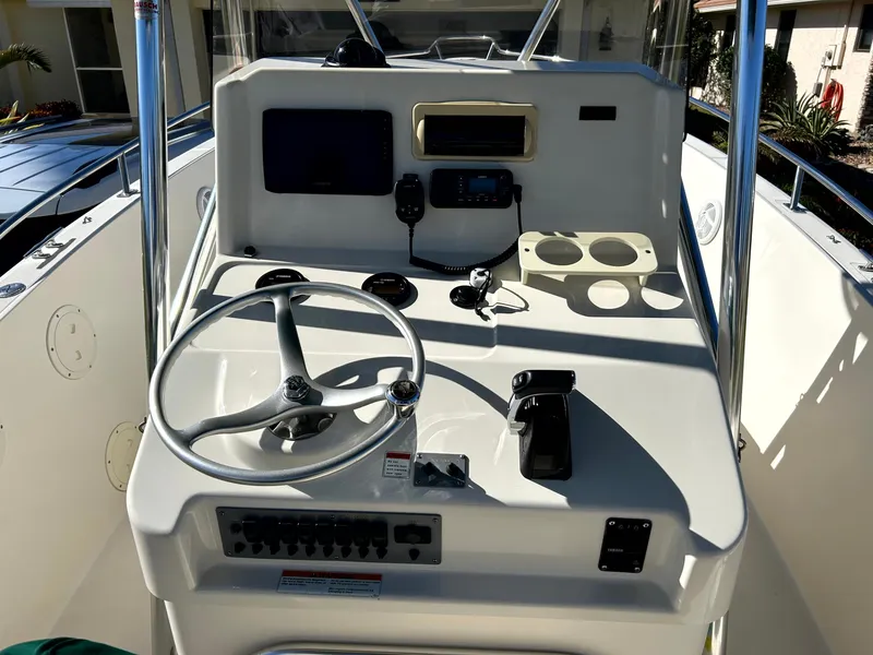 Slide: The Image of 2003 Pursuit 2470 Center Console boat dashboard with steering wheel and controls. - 15