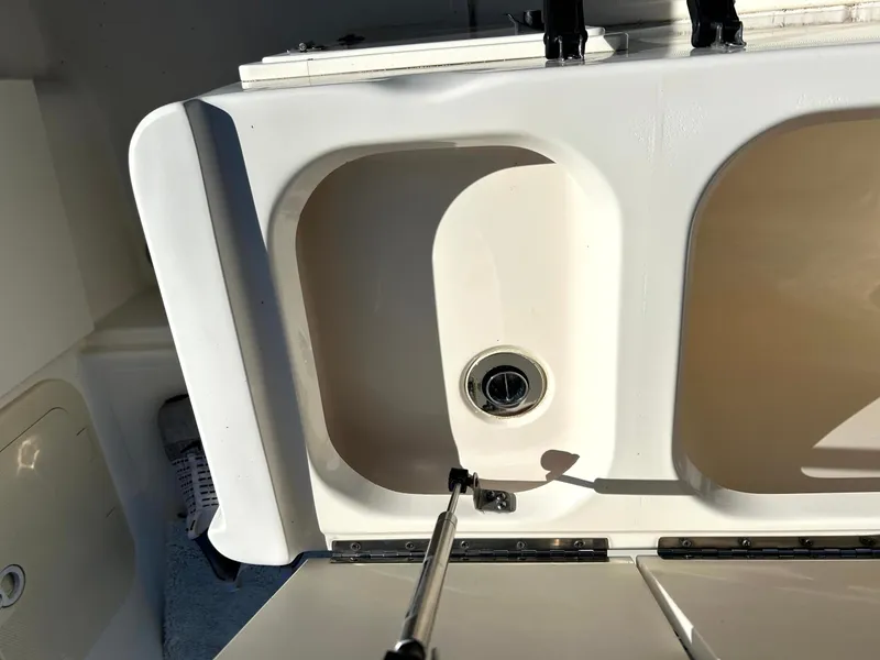 Slide: The Image of 2003 Pursuit 2470 Center Console boat compartment with open lid and hydraulic support. - 19