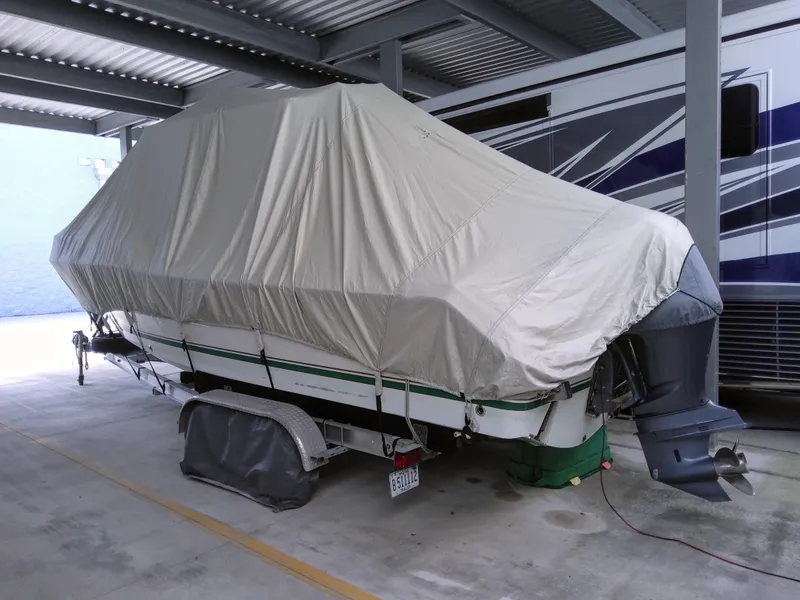 Slide: The Image of 2003 Pursuit 2470 Center Console boat covered and parked in a sheltered area. - 2