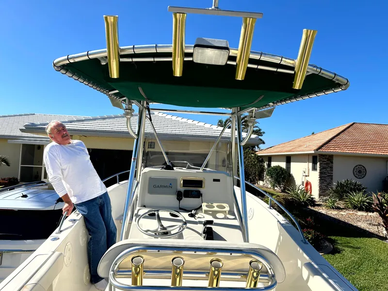 Slide: The Image of 2003 Pursuit 2470 Center Console boat with T-top and rod holders, parked near houses. - 27