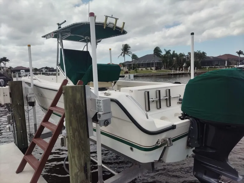 Slide: The Image of 2003 Pursuit 2470 Center Console boat docked, featuring green covers and a ladder. - 3