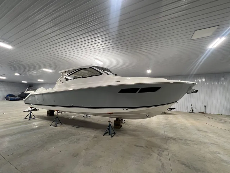 Slide: The Image of 2026 Pursuit DC 365 Dual Console boat in indoor storage facility. - 0