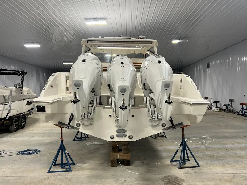 Slide: The Image of 2026 Pursuit DC 365 Dual Console boat with triple outboard engines in a storage facility. - 10