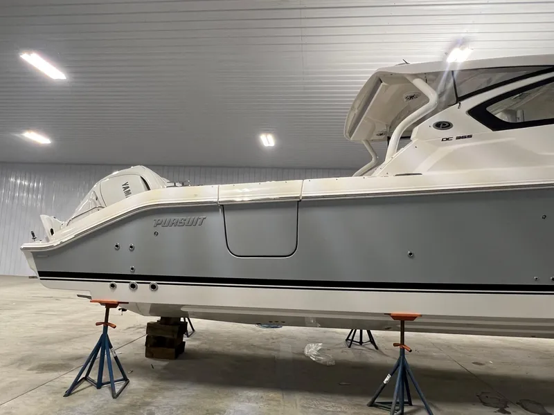 Slide: The Image of 2026 Pursuit DC 365 Dual Console boat in indoor storage on stands. - 2