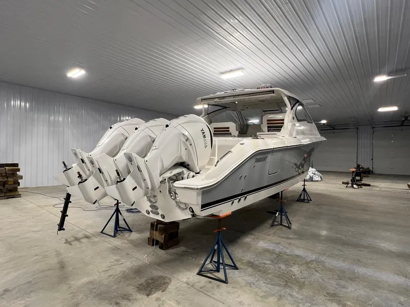 Slide: The Image of 2026 Pursuit DC 365 Dual Console boat with triple engines in a spacious indoor storage facility. - 4
