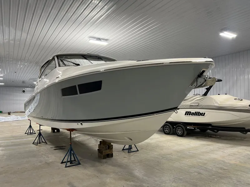 Slide: The Image of 2026 Pursuit DC 365 Dual Console boat in indoor storage on stands. - 5