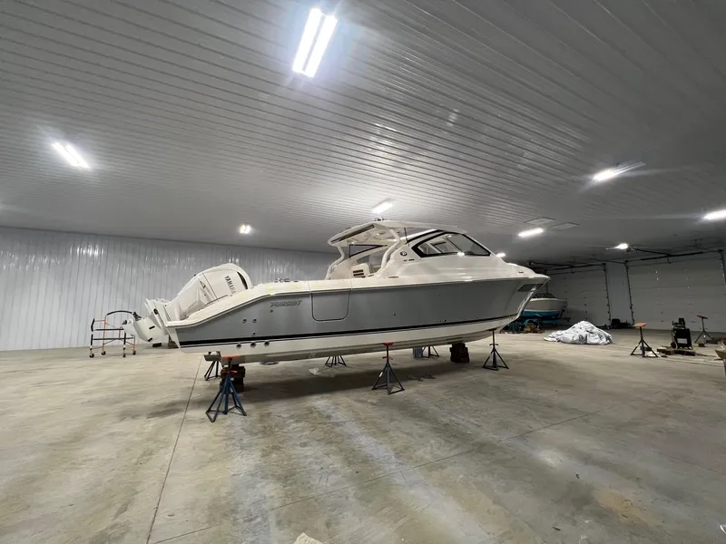 Slide: The Image of 2026 Pursuit DC 365 Dual Console boat in spacious indoor storage facility. - 9