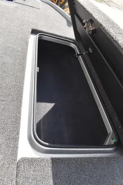 Slide: The Image of 2025 Triton 21XP Patriot boat storage compartment, open and empty, with carpeted interior. - 19