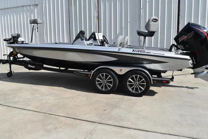 Slide: The Image of 2025 Triton 21XP Patriot boat on trailer, parked outdoors. - 2