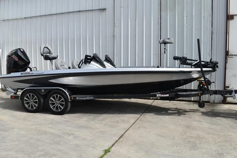 Slide: The Image of 2025 Triton 21XP Patriot boat on trailer, parked by a metal building. - 3