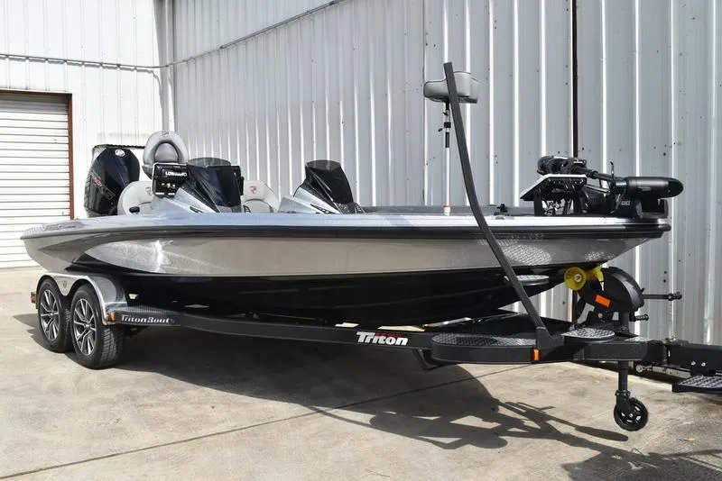 Slide: The Image of 2025 Triton 21XP Patriot boat on trailer, parked near a metal building. - 4