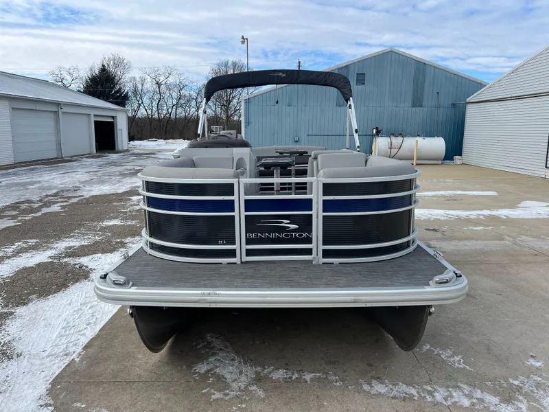Slide: The Image of 2021 Bennington L 21 Swingback pontoon boat on snowy driveway, blue and gray design. - 2