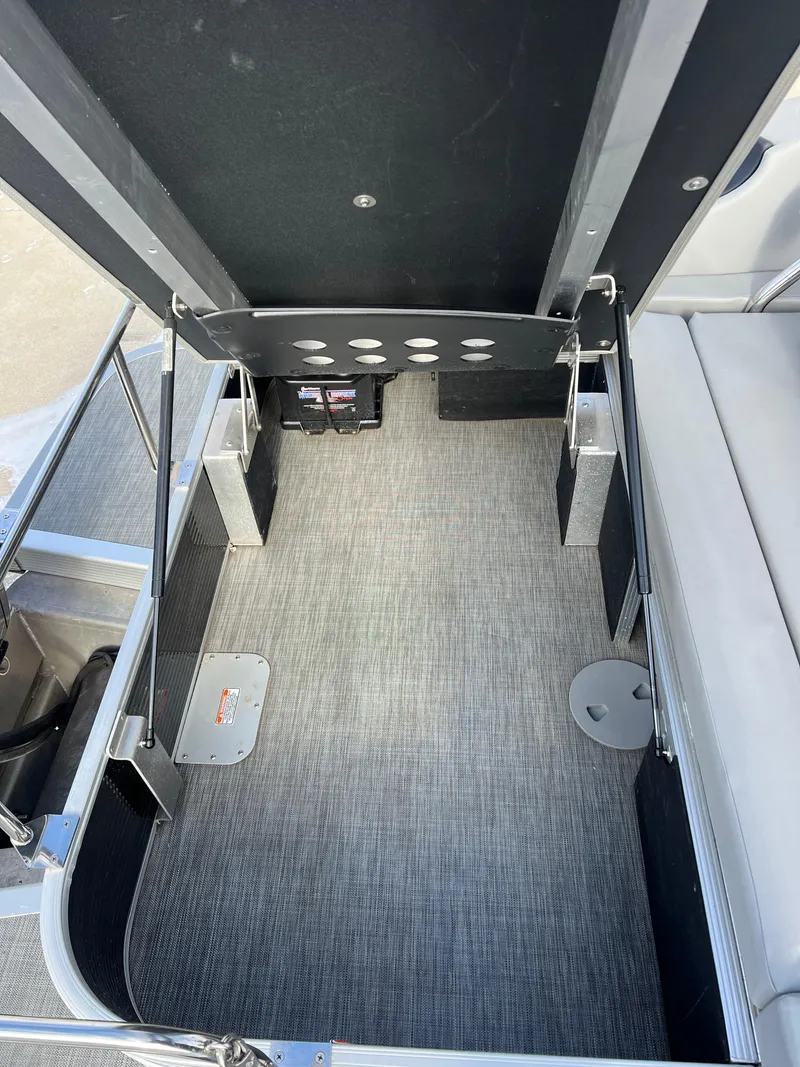 Slide: The Image of 2021 Bennington L 21 Swingback interior with open storage compartment and gray flooring. - 25