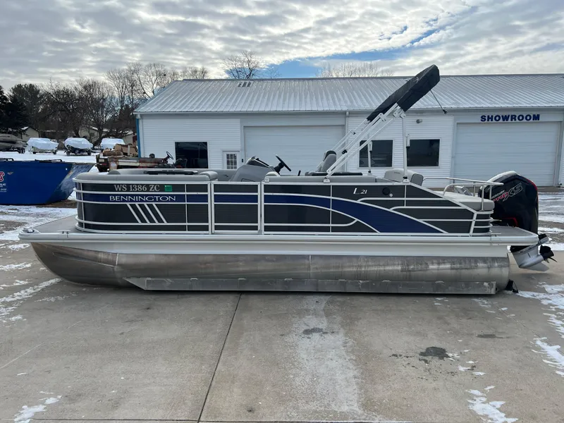Slide: The Image of 2021 Bennington L 21 Swingback pontoon boat parked outside a showroom on a snowy day. - 4