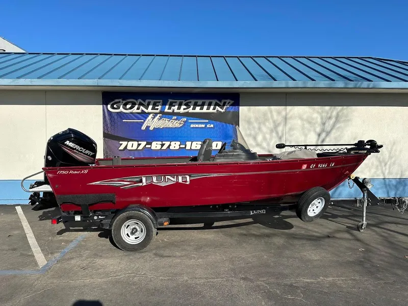 Slide: The Image of 2015 Lund 1750 Rebel XS SS boat, red, on trailer, parked outside dealership. - 1