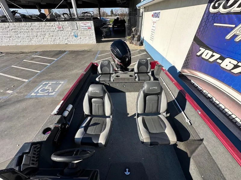 Slide: The Image of 2015 Lund 1750 Rebel XS SS boat interior with seating and motor, parked outdoors. - 31