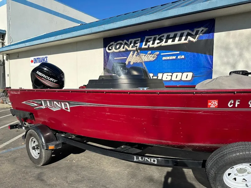 Slide: The Image of 2015 Lund 1750 Rebel XS SS boat with Mercury engine, parked outside a fishing store. - 6