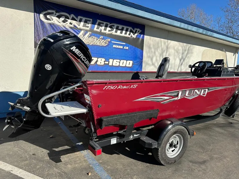 Slide: The Image of 2015 Lund 1750 Rebel XS SS boat with Mercury engine, parked outside a marine store. - 8