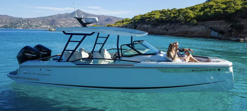 Slide: The Image of 2024 Saxdor 270 GTO boat cruising in clear blue waters near a scenic coastline. - 2