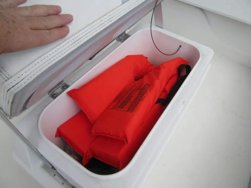 Slide: The Image of Storage compartment with orange life jackets in a 2013 Sundance B20CCR boat. - 14