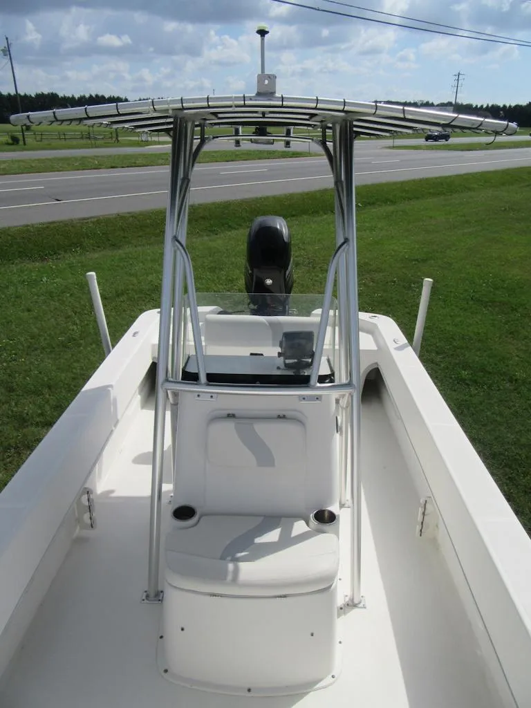 Slide: The Image of 2013 Sundance B20CCR boat with T-top, center console, and outboard motor on grassy roadside. - 6