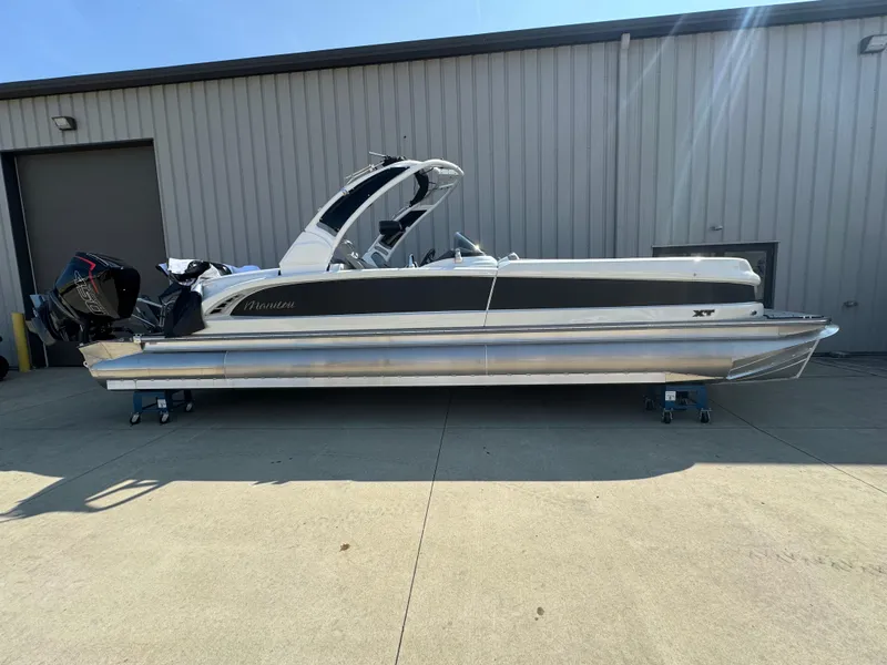 Slide: The Image of 2024 Manitou 27 XT RFXW pontoon boat parked outside a warehouse. - 0