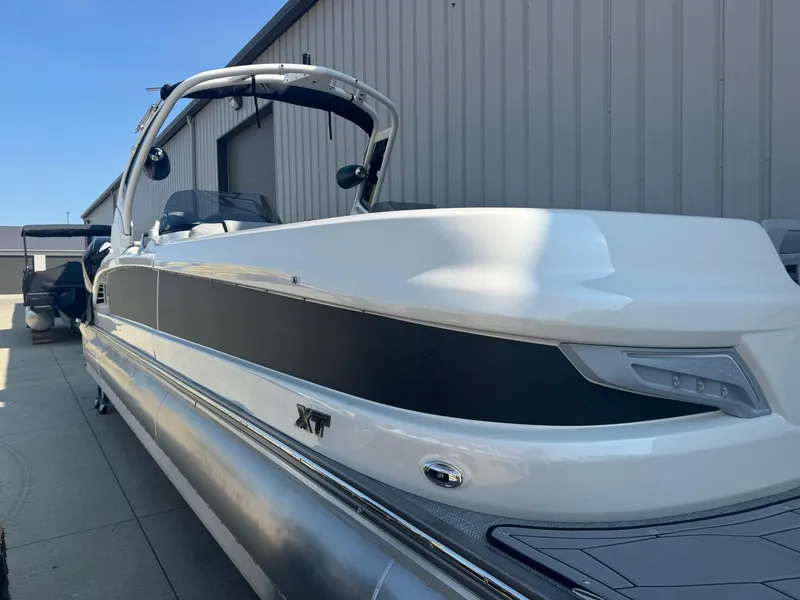 Slide: The Image of 2024 Manitou 27 XT RFXW pontoon boat, sleek design, docked outdoors. - 1