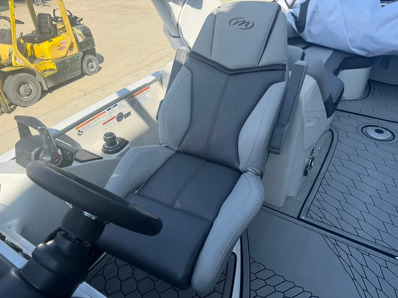 Slide: The Image of 2024 Manitou 27 XT RFXW boat interior with sleek captain's chair and steering wheel. - 11