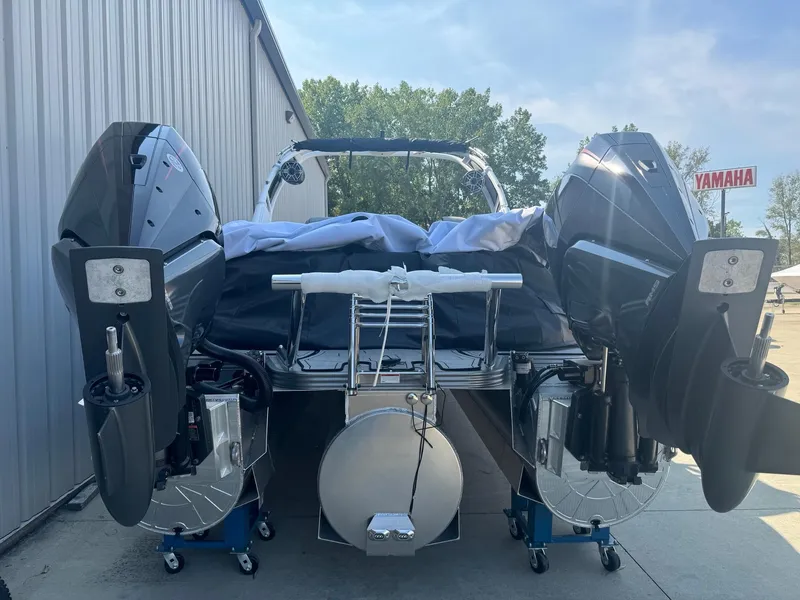 Slide: The Image of 2024 Manitou 27 XT RFXW boat with dual engines, parked outdoors near a Yamaha sign. - 21