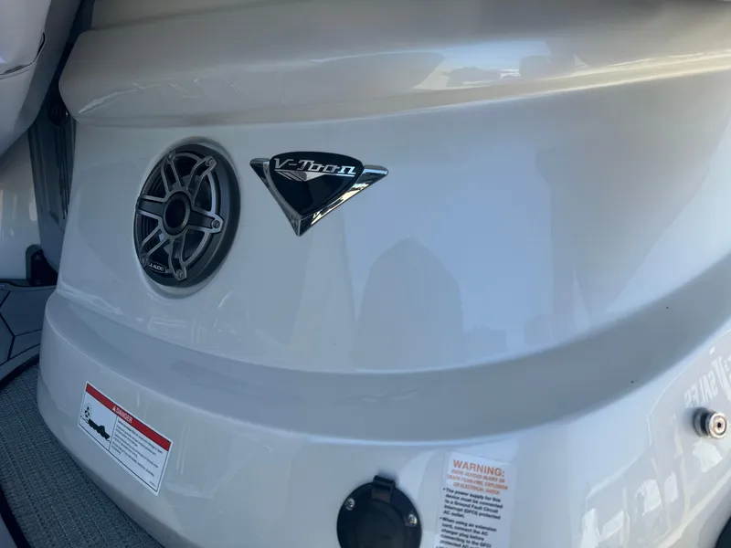 Slide: The Image of 2024 Manitou 27 XT RFXW boat detail with speaker and V-Toon emblem. - 3