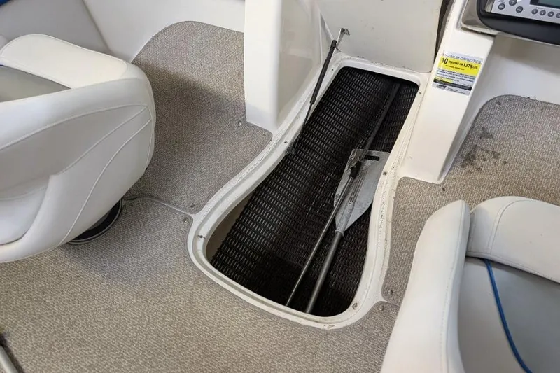 Slide: The Image of 2012 Rinker Captiva 216 BR boat interior with open storage compartment and paddle. - 11