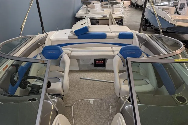 Slide: The Image of 2012 Rinker Captiva 216 BR boat interior with blue and white seating, in showroom. - 8