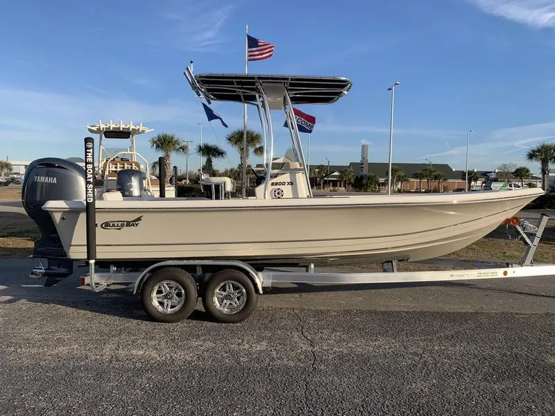 Slide: The Image of 2025 Bulls Bay 2200 XS boat on trailer with Yamaha engine, flags in background. - 5