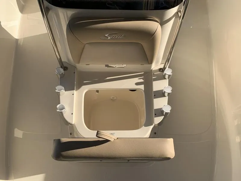 Slide: The Image of 2025 Scout 177 Sport boat interior with seating and console in a marina setting. - 9