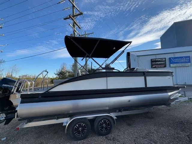 Slide: The Image of 2025 Barletta ARIA 22UC pontoon boat on trailer, parked outdoors. - 2