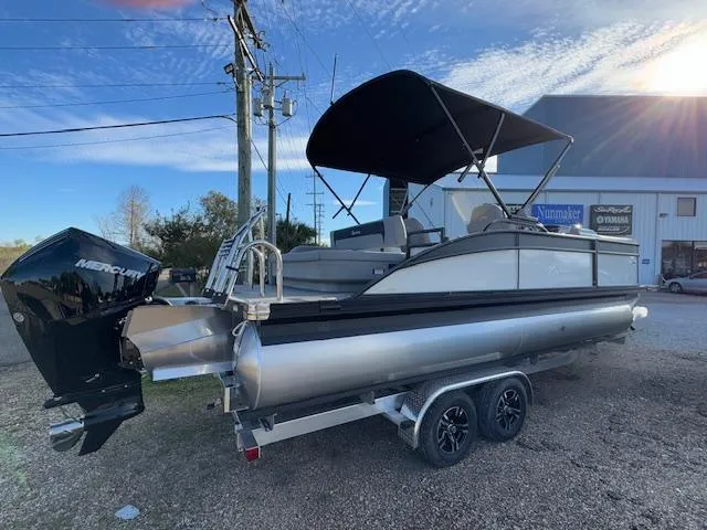 Slide: The Image of 2025 Barletta ARIA 22UC pontoon boat with Mercury engine on trailer, parked outdoors. - 3