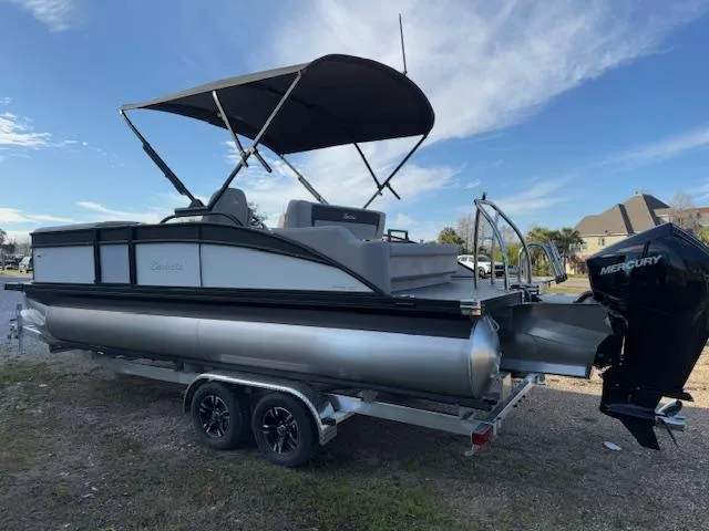 Slide: The Image of 2025 Barletta ARIA 22UC pontoon boat with Mercury engine on trailer, under blue sky. - 4