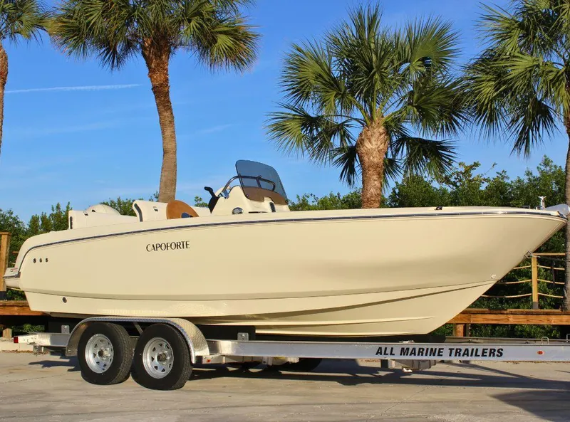Slide: The Image of 2024 Capoforte SX200 boat on trailer, surrounded by palm trees. - 2