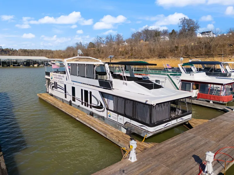 Slide: The Image of Houseboat docked on a lake, Horizon 18 X 82 model, 2011, under a clear sky. - 4