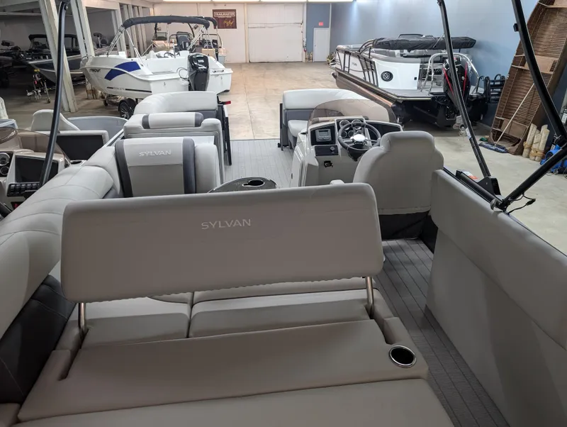 Slide: The Image of 2025 Sylvan Mirage 8522 CLZ pontoon boat interior in showroom, featuring spacious seating. - 11