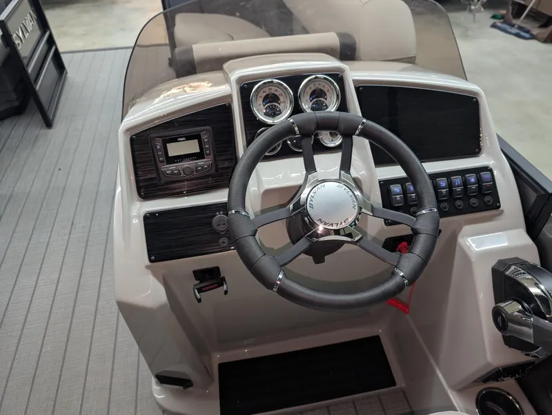 Slide: The Image of 2025 Sylvan Mirage 8522 CLZ boat dashboard with steering wheel and controls. - 8