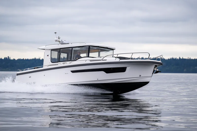Slide: The Image of 2022 Nimbus C11 boat cruising on a calm lake under cloudy skies. - 0