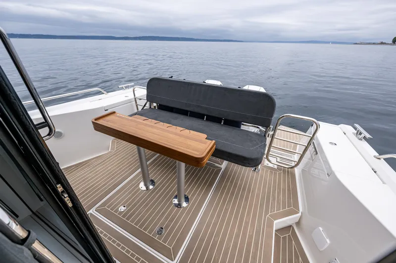 Slide: The Image of Nimbus C11 2022 boat deck with seating and wooden table on calm water. - 23