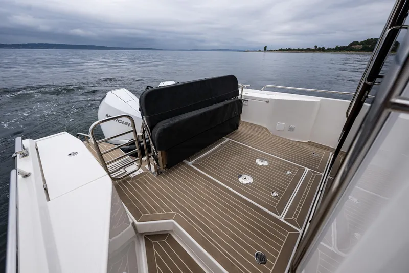Slide: The Image of 2022 Nimbus C11 boat deck with seating, overlooking calm waters under cloudy skies. - 26